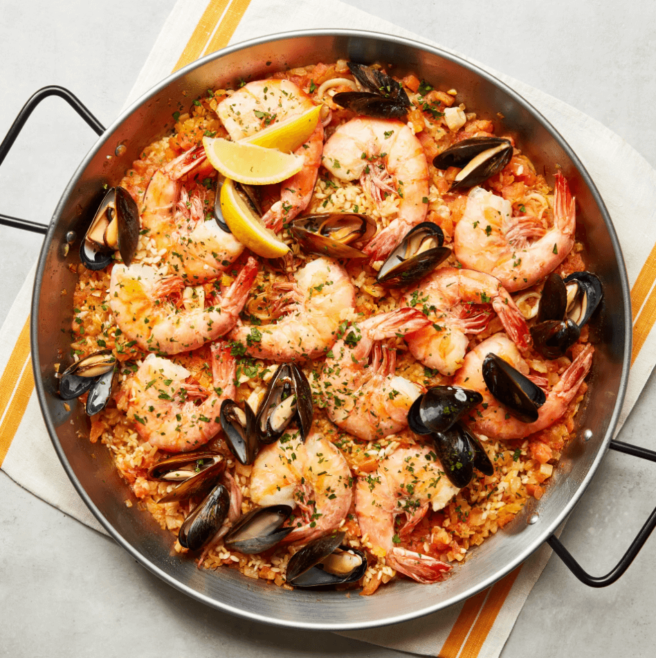 Seafood paella in a pan with mussels and king prawns