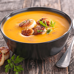 Pumpkin soup in a bowl with sauteed scallops